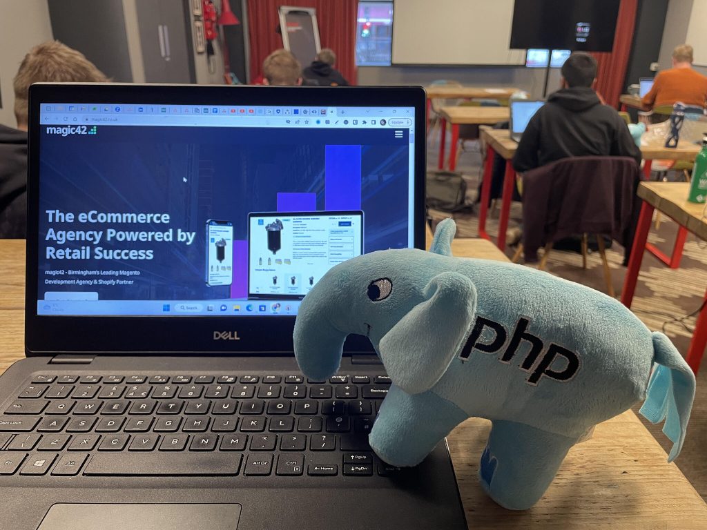 The magic42 eCommerce development agency, website and its team, complete with a php elephant plush atop a laptop